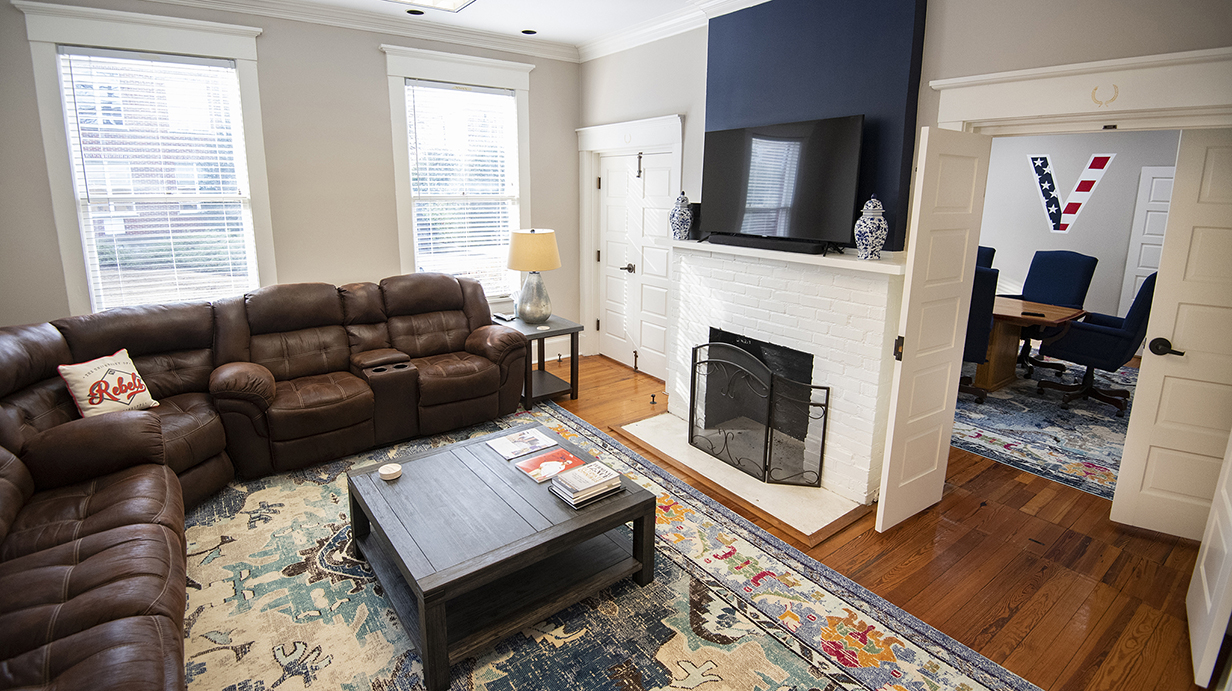 A living room is furnished with comfortable couches and a large television above a fireplace.