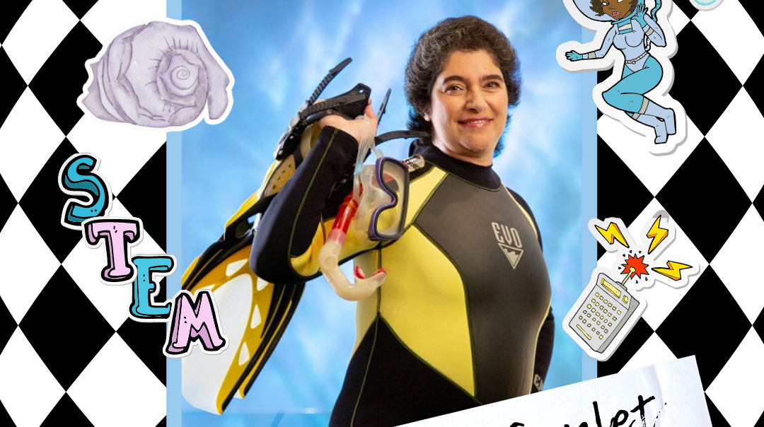A woman wearing a wetsuit holds diving gear.