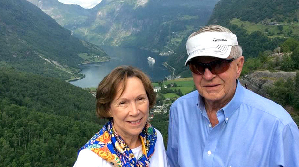 A man and woman stand in front of a scenic overlook.
