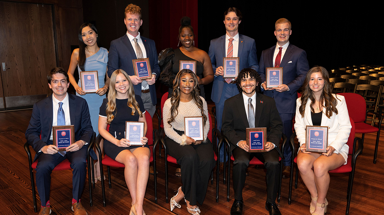 A group of young men and women, all holding award plaques, gather for a photo on a stage.