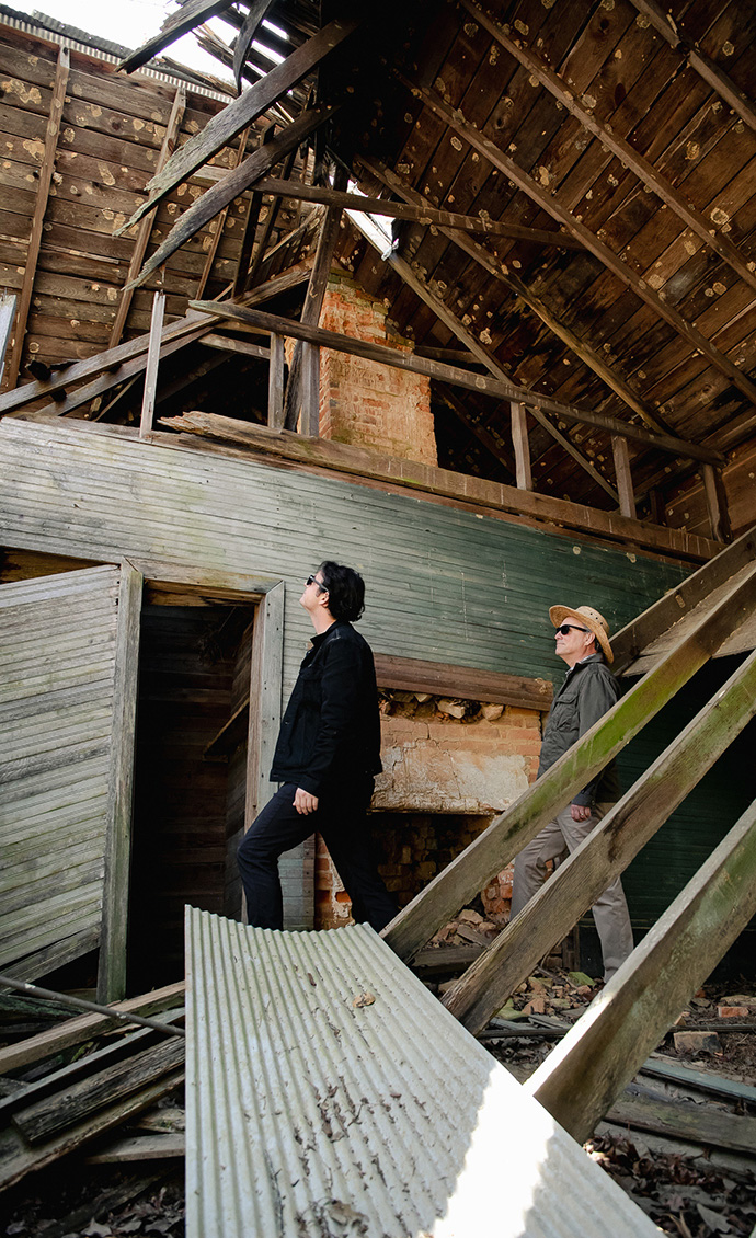 A man inspects a partially collapsed wood building.