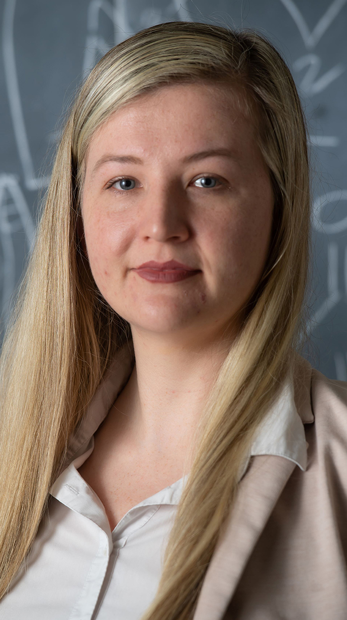 Headshot of a woman wearing a tan jacket over a white blouse.