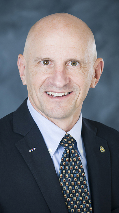 Headshot of a bald man wearing a dark suit.