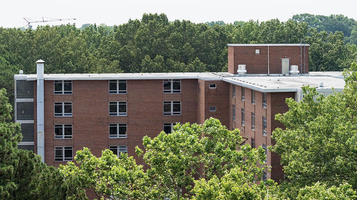 Exterior of a large red brick building surrounded by trees.