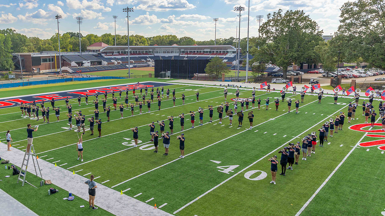 A marching band practices on a field lined for football.