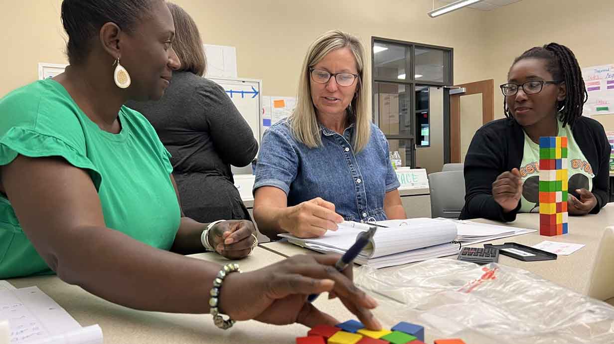 Corliss Wesley, Carla Martin and Jasmine Russell explore the volume of rectangular prisms using wooden inch cubes as part of the Middle Math Institutes at the Center for Mathematics and Science Education.