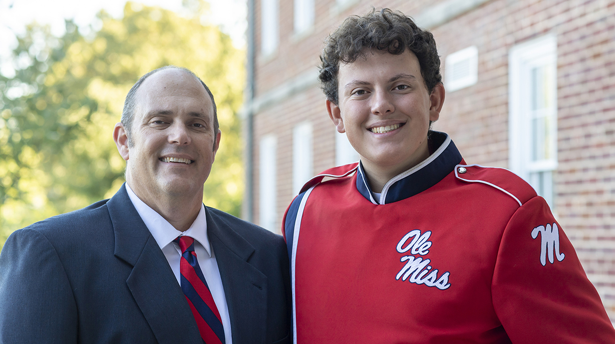 Photo of a man in a suit and a young man wearing a band unioform.