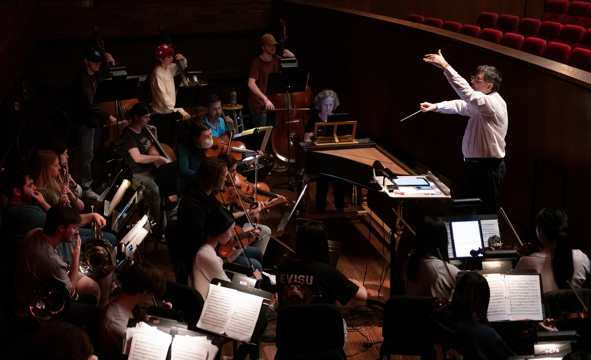 A conductor leads an orchestra in performance. 