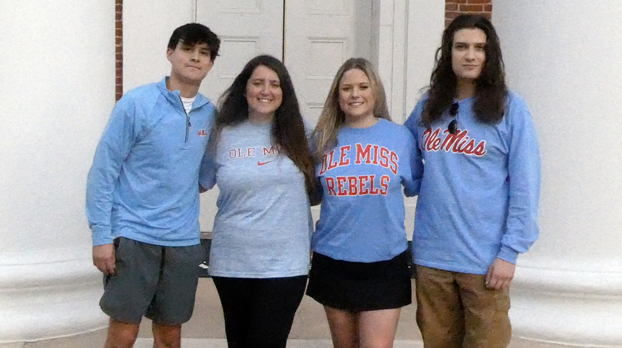 Two male and two female students stand in front of the Lyceum.