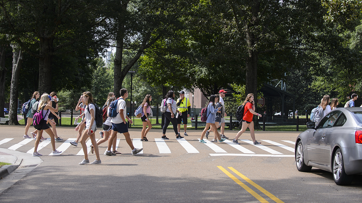 Students corssing a street on campus while a car waits for the intersection to clear