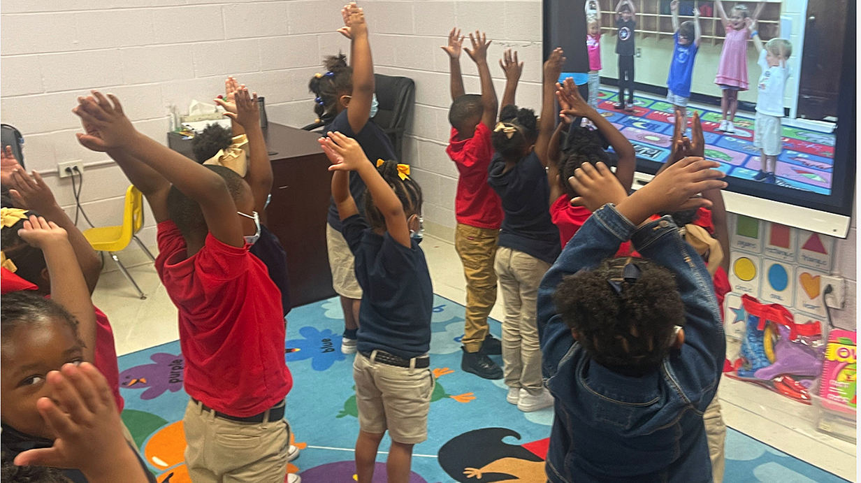 A group of schoolchildren take part in a wellness exercise.