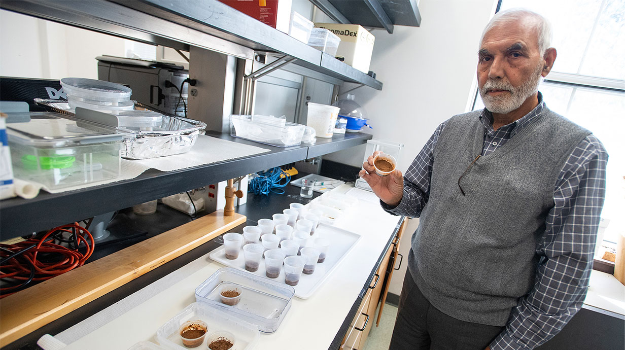 Professor holds up a sample in a lab. 