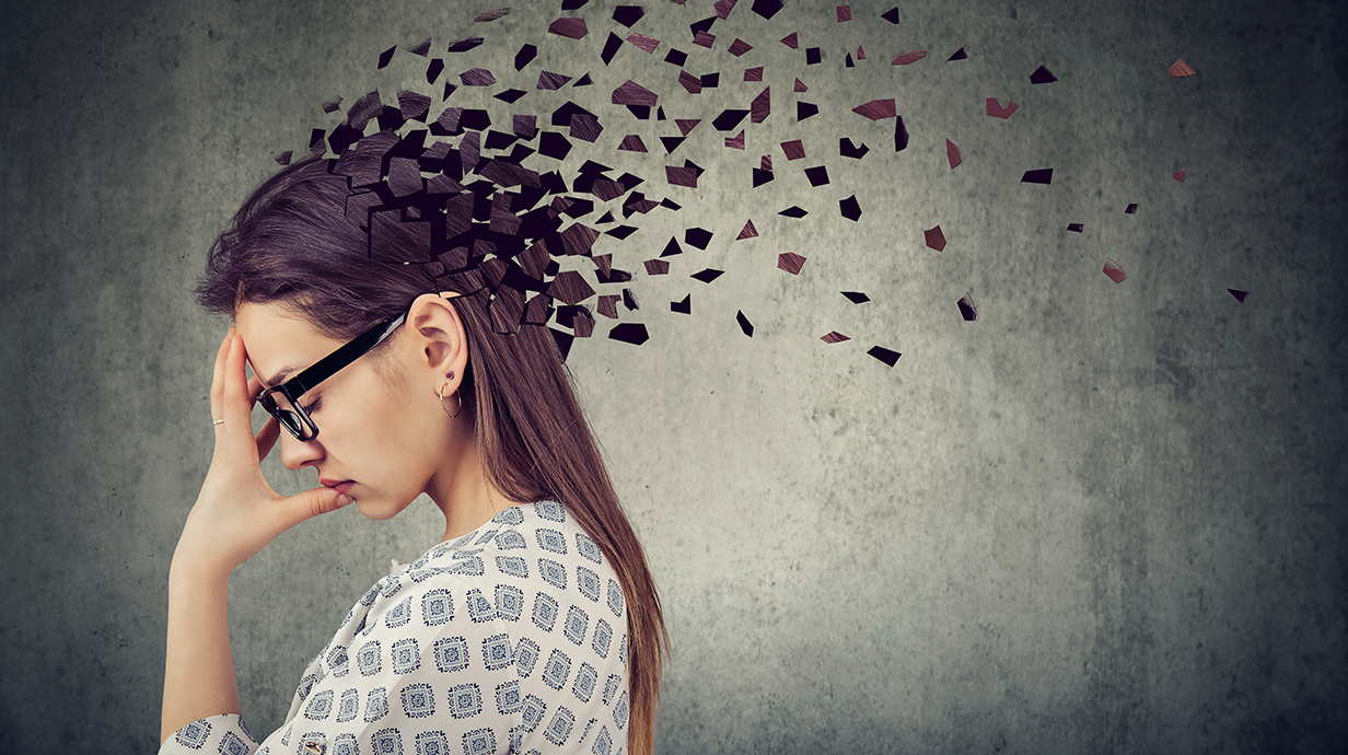 A woman holds her head as pieces representing memories blow away.