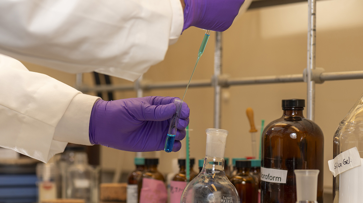 A scientists pipes blue liquid into a vial.