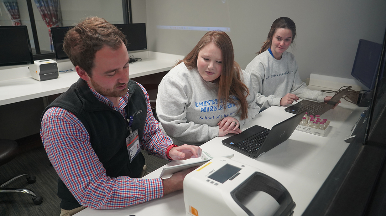 Three pharmacy students examine new technology in a skills lab.