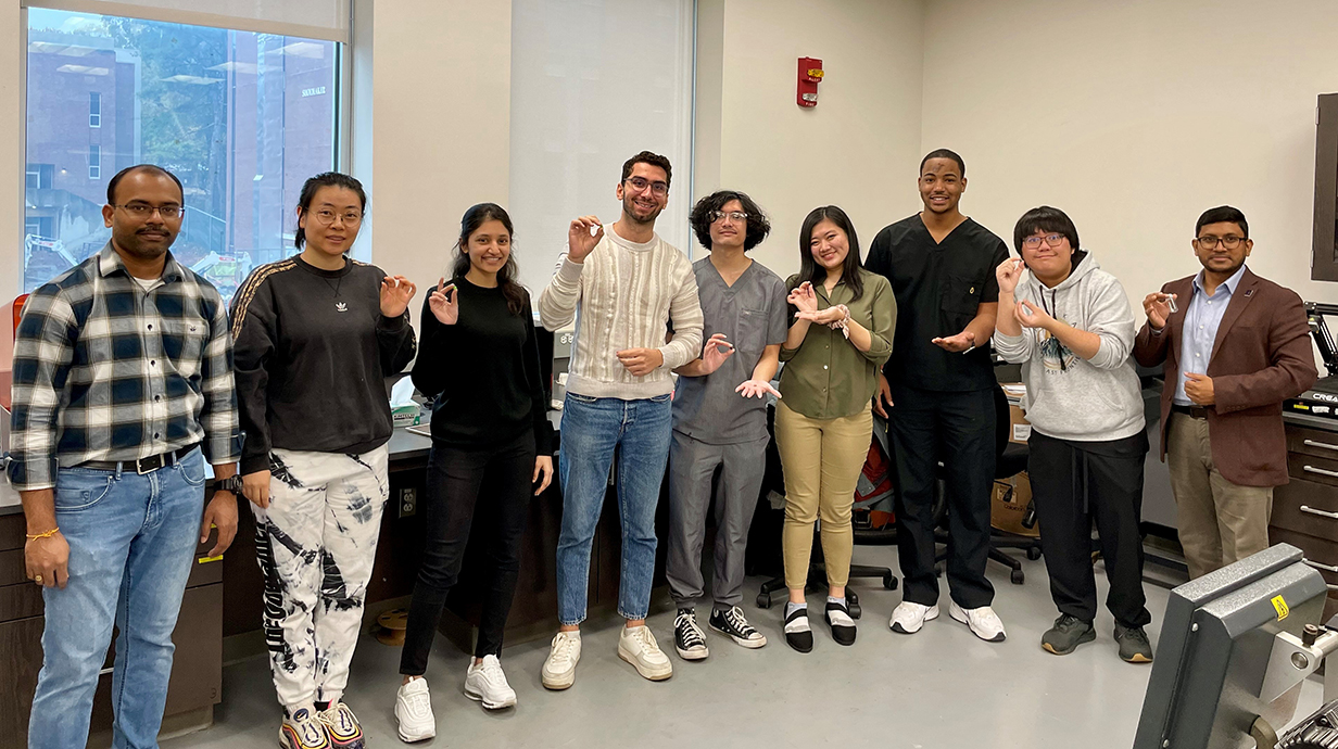 Researchers stand in a lab holding samples of 3D-printed pills.