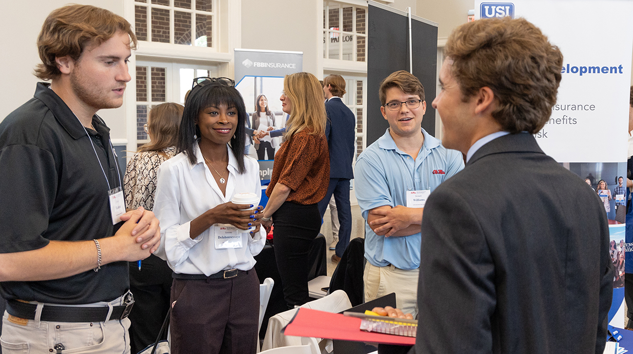 A group of people talks to a oung man at a career fair.