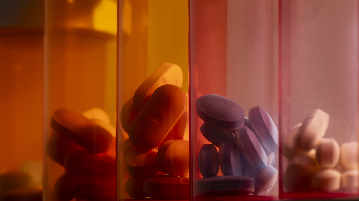A row of colored bottles partially filled with pills
