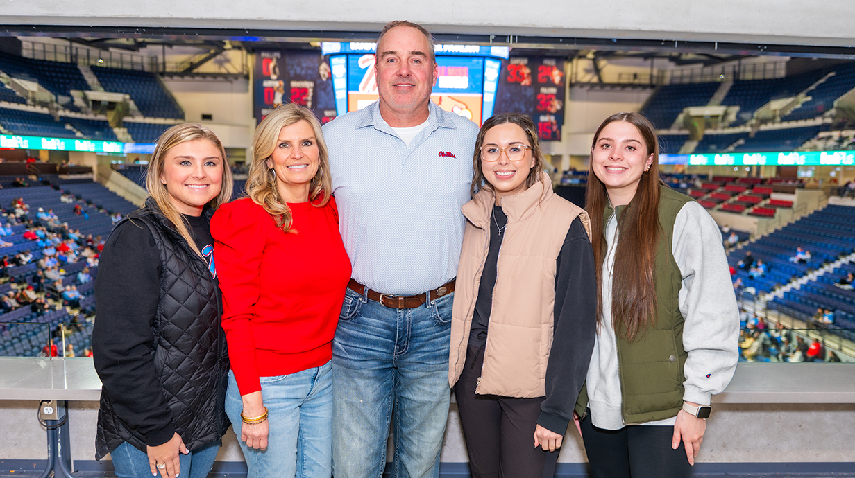 A family stands in a basketball arena.