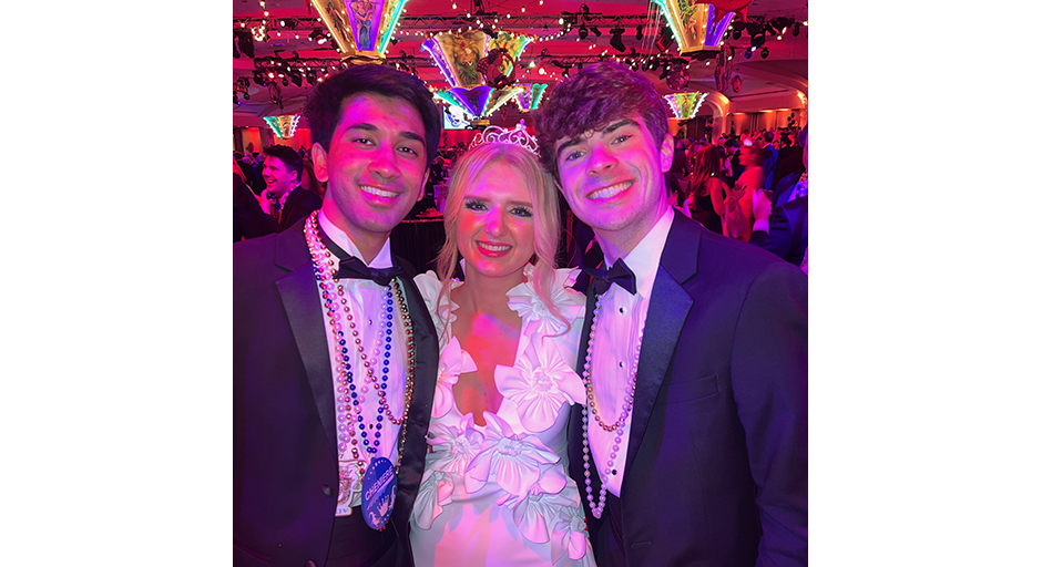 Two young men and a young woman pose at a gala.