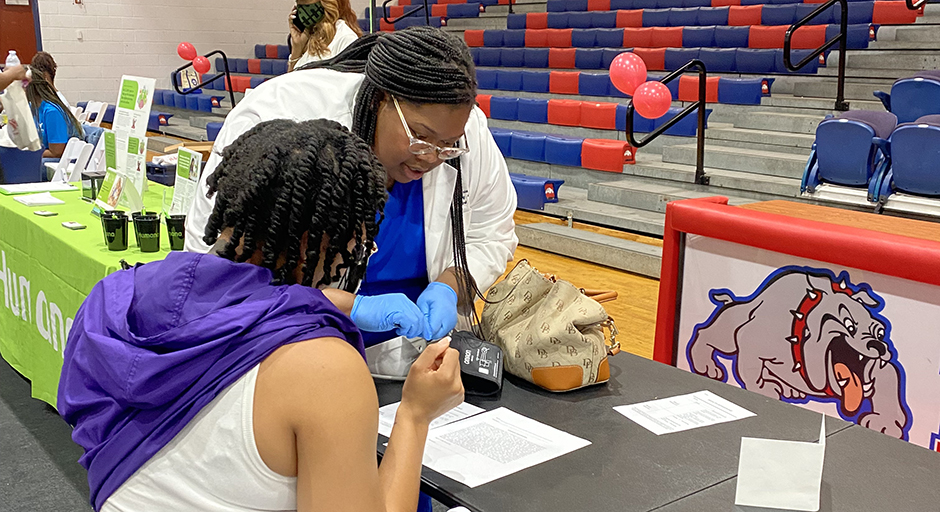 A young woman helps a man fill out paperwork at a health fair.