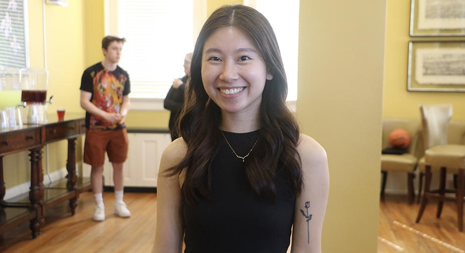 A young woman in a black dress stands in a reception hall.