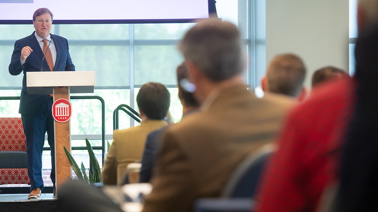 A little man speaks to a conference audience.