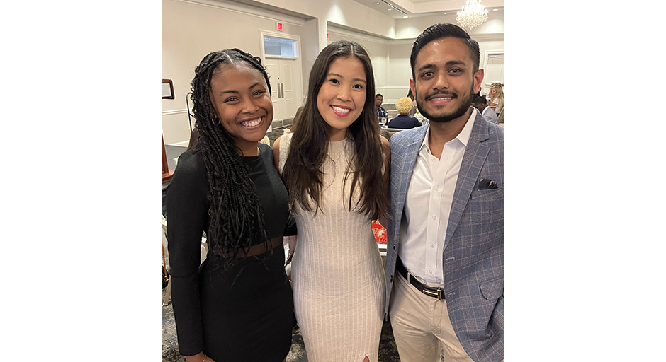 Two young women and a young man stand in a banquet room.