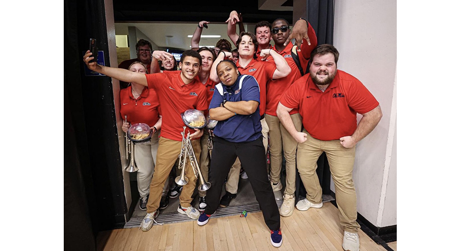 A group of young people in red shirts pose around a woman in a blue shirt. 