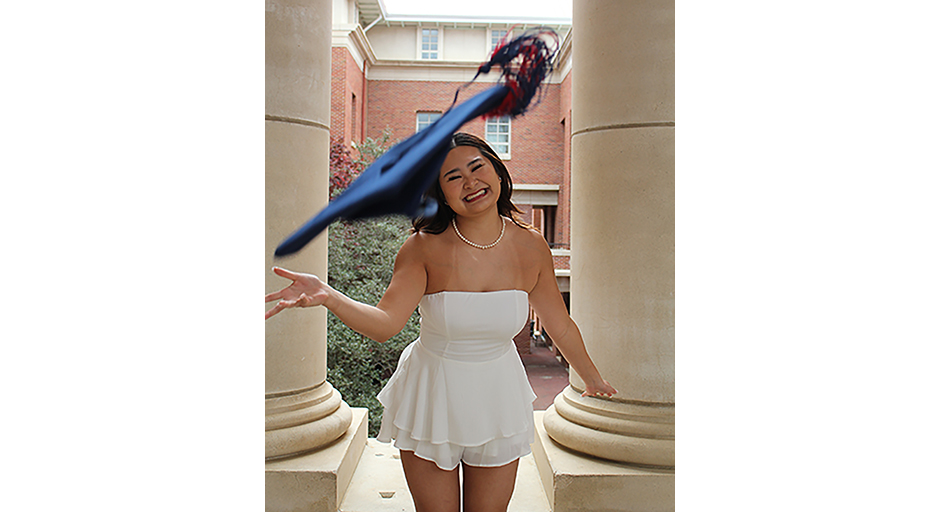 A young woman throws a graduation cap at the camera.