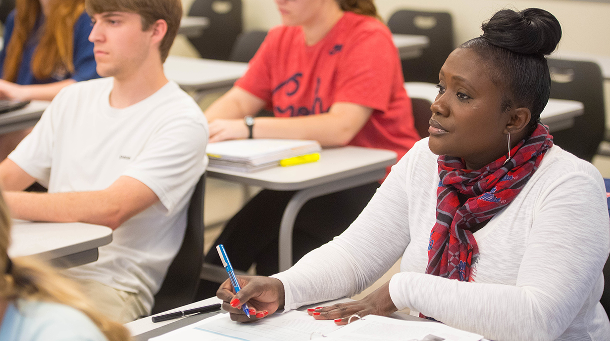 A woman takes notes in a classroom.