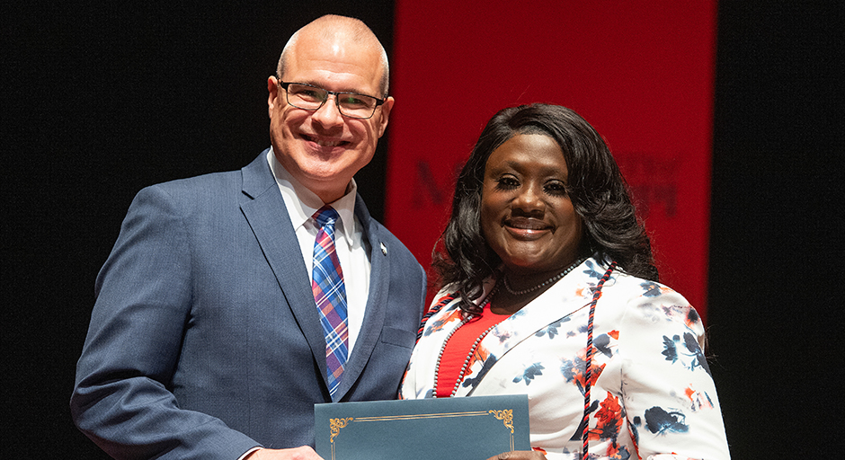 A man presents an award certificate to a woman.