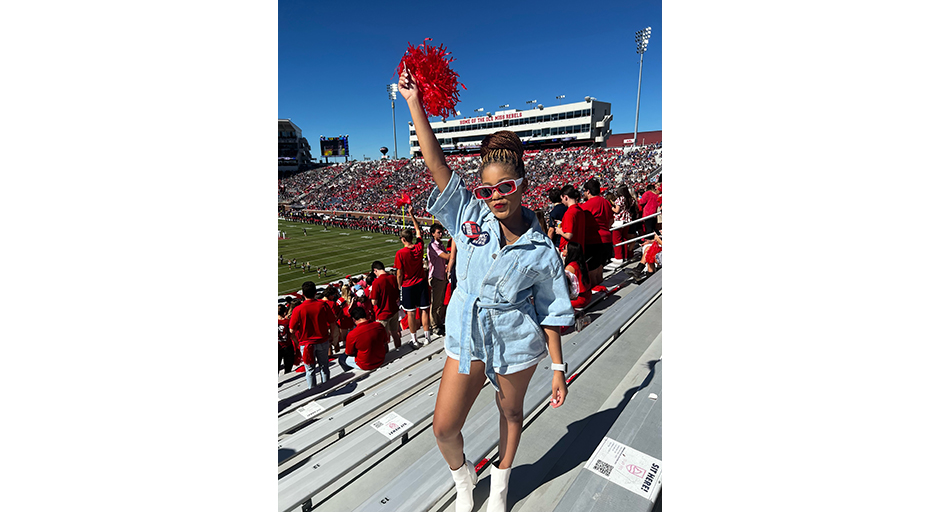 A young woman shake a pompon in a football stadium