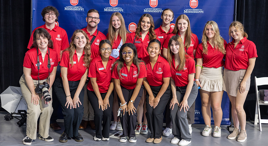 A group of young people wearing matching red shirts pose for a group photo.