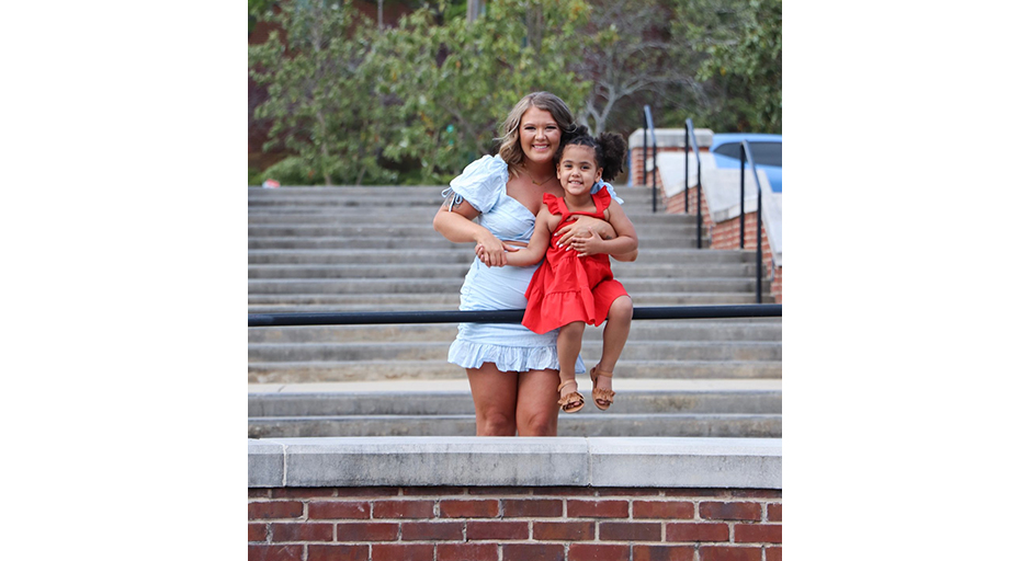 A young woman and a child pose on a set of concrete stairs.