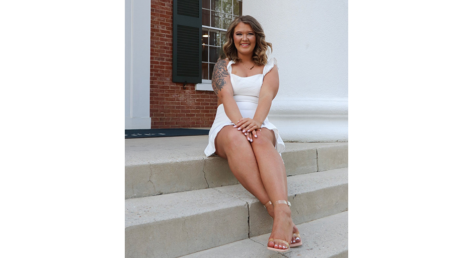 A young woman sits on concrete steps leading to a porch.