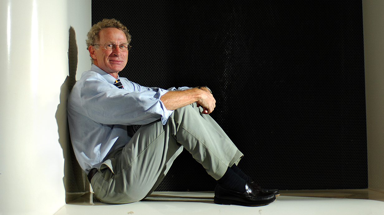 A man sits in a giant box, leaning against the side.