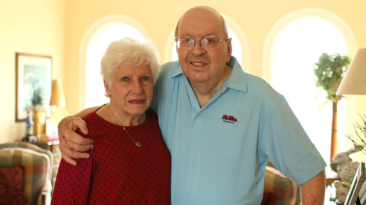A man and woman pose for a photo in their home.