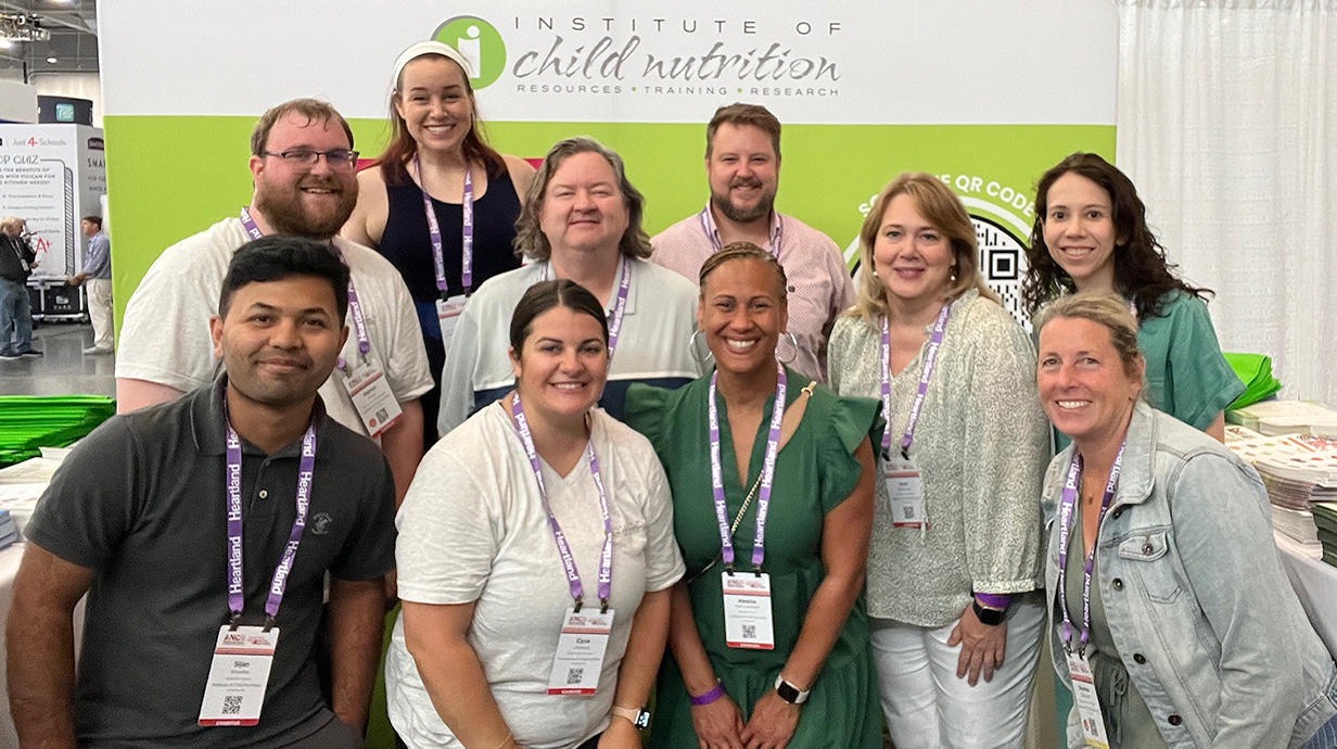 A group of people pose in front of a banner reading 'Institute of Child Nutrition.'