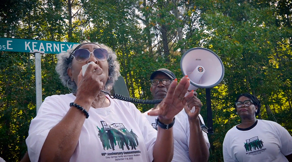 A woman talks into a bullhorn at a protest.