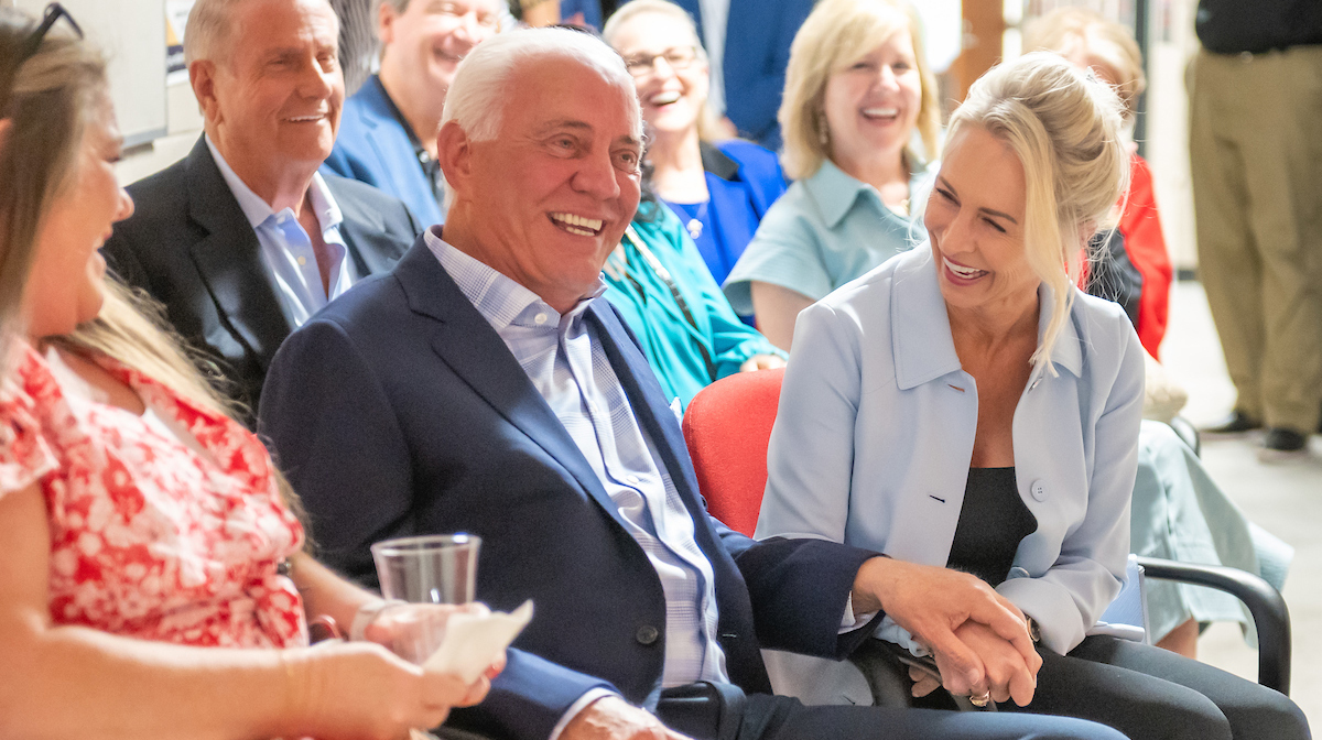 A man and a woman seated in a crowd share a laugh.