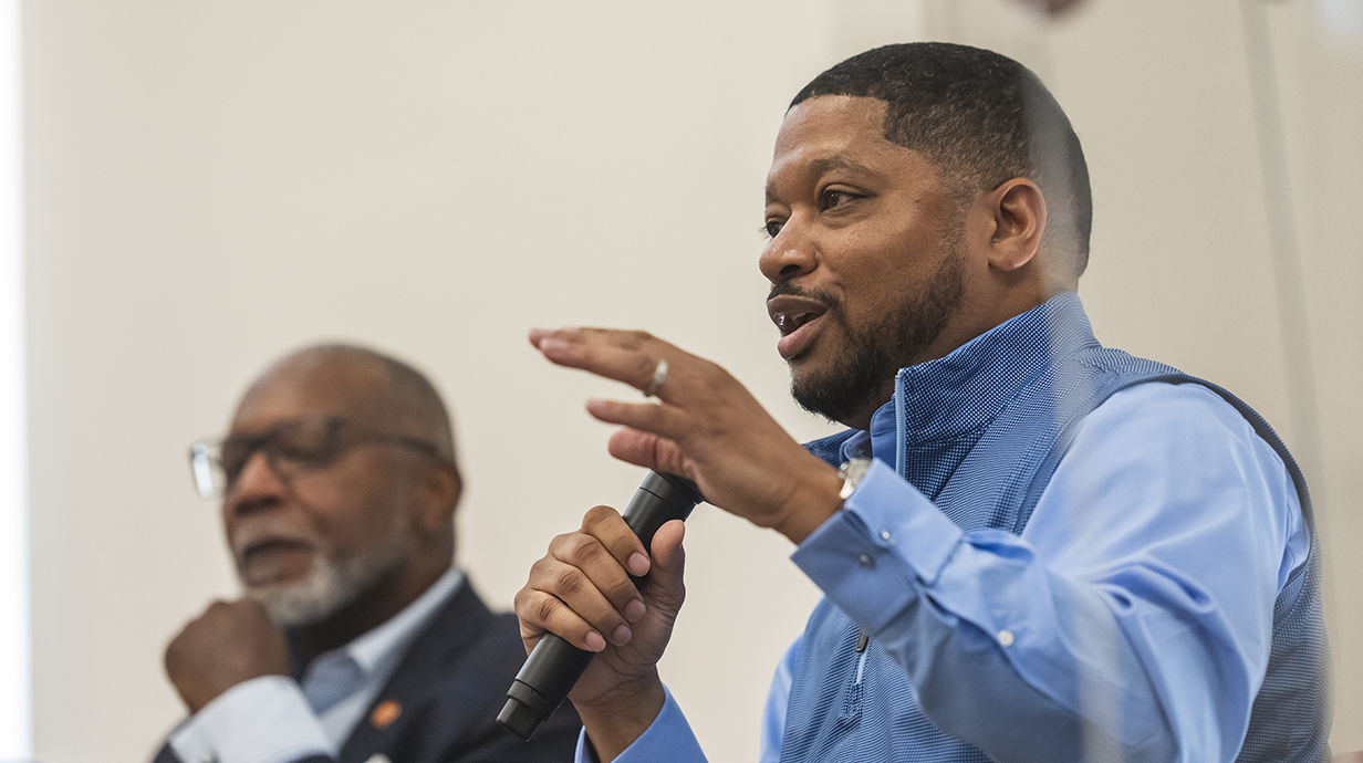 A man gestures as he talks during a panel discussion.