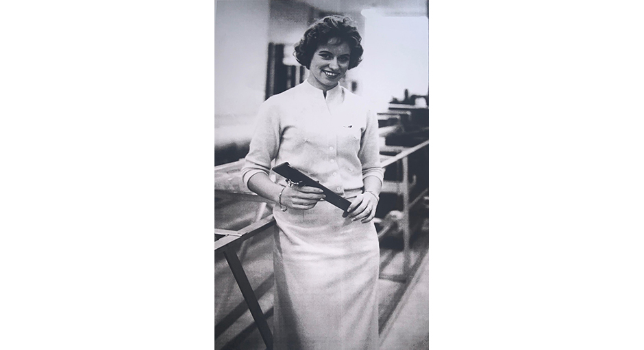 A woman wearing a white dress poses for a photo in an engineering lab.