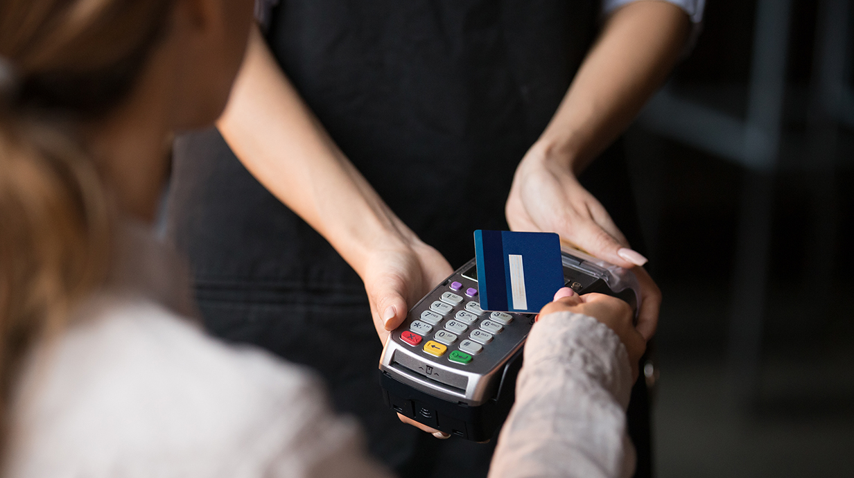 A woman's hand holds a credit card above a scanner.