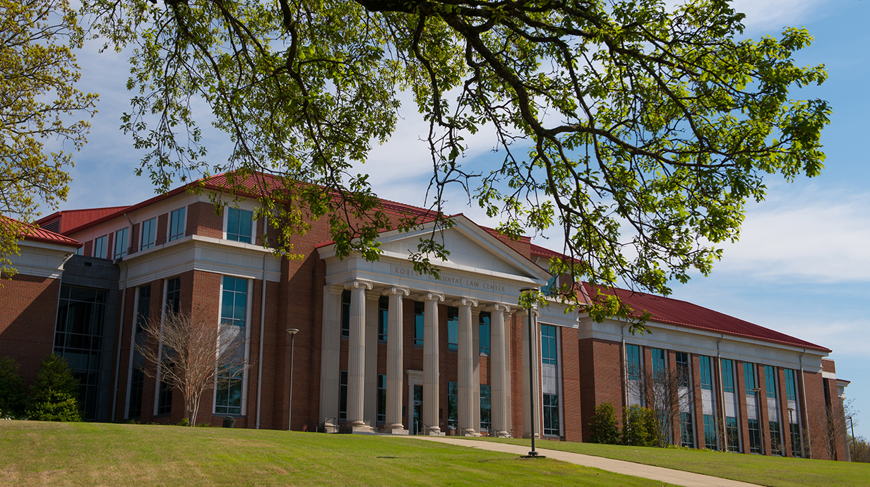 Photograph of a large red brick academic building with white columns on the facade.