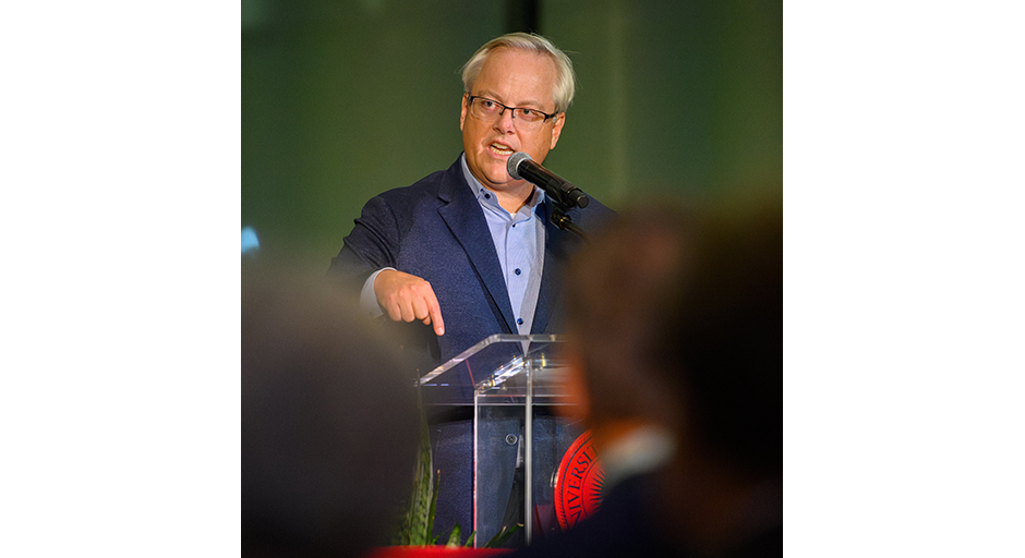 A man wearing a suit speaks from a podium.