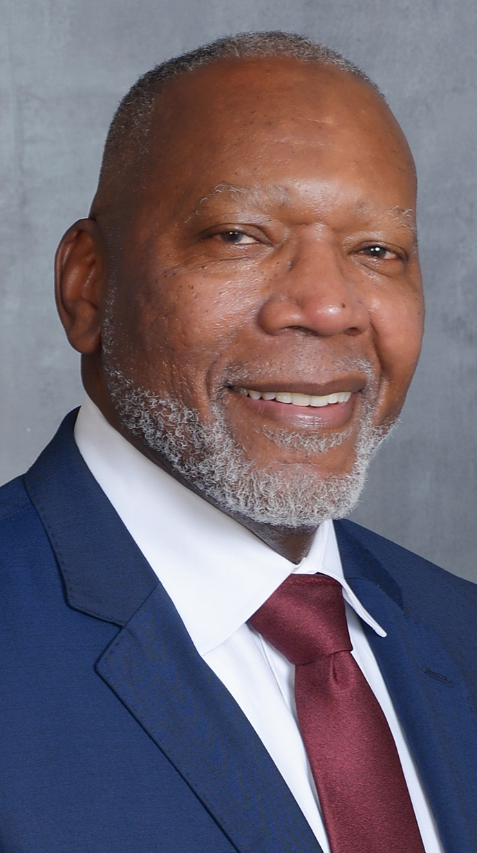 Headshot of a man wearing a blue suit and a red tie.