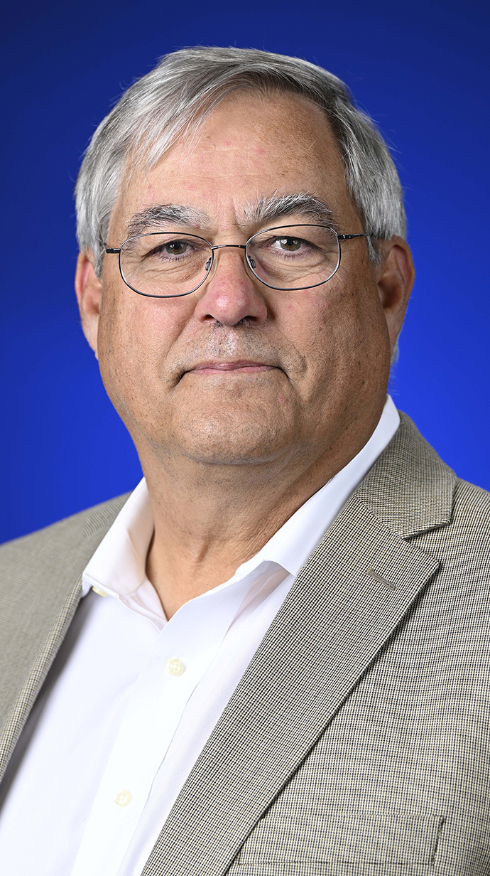 Headshot of a man wearing a tan jacket.