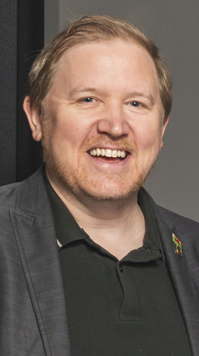 Headshot of a man wearing a brown jacket.