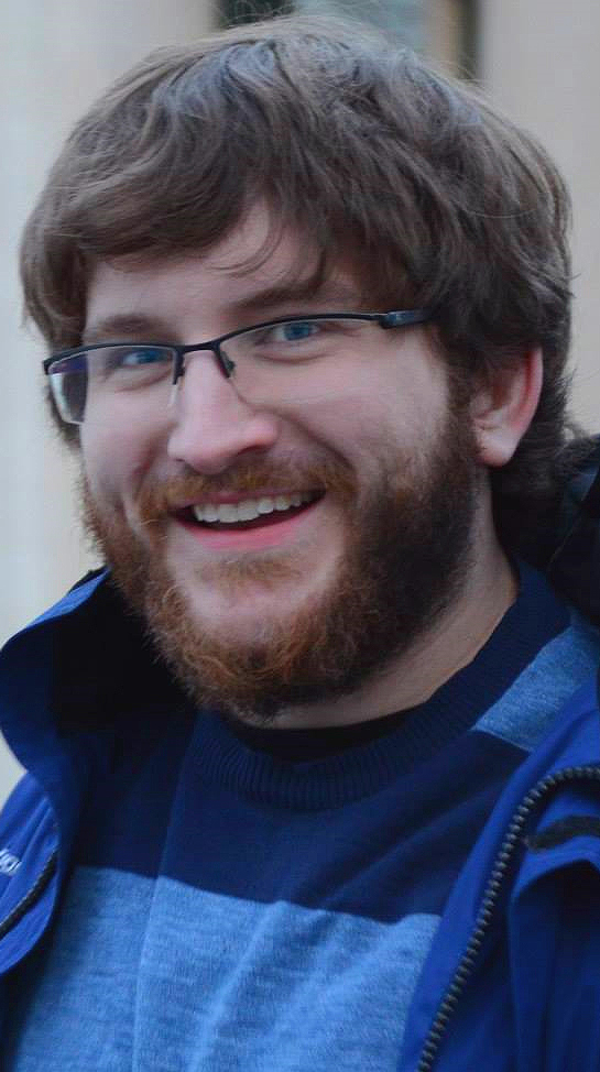 Headshot of a young man wearing a blue-and-black shirt.